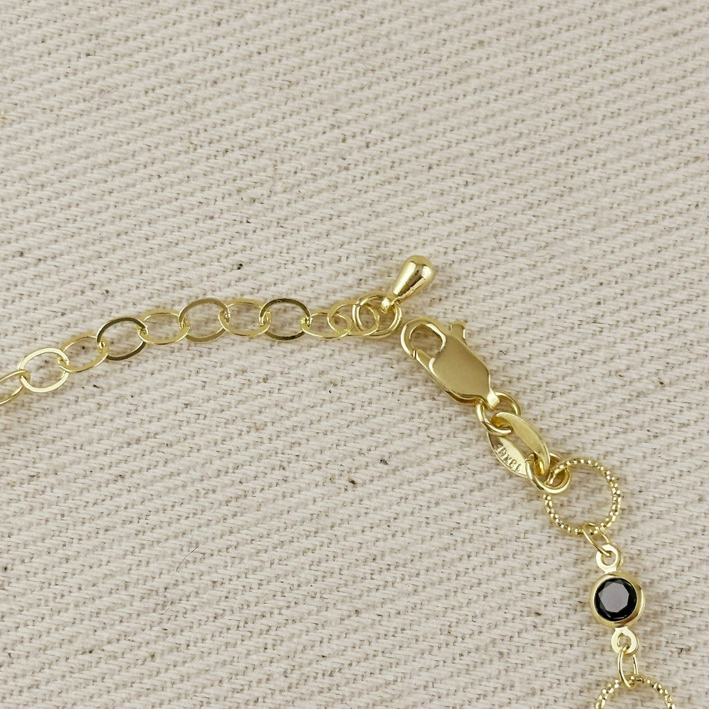 Gold bracelet with a black gemstone on a beige fabric background