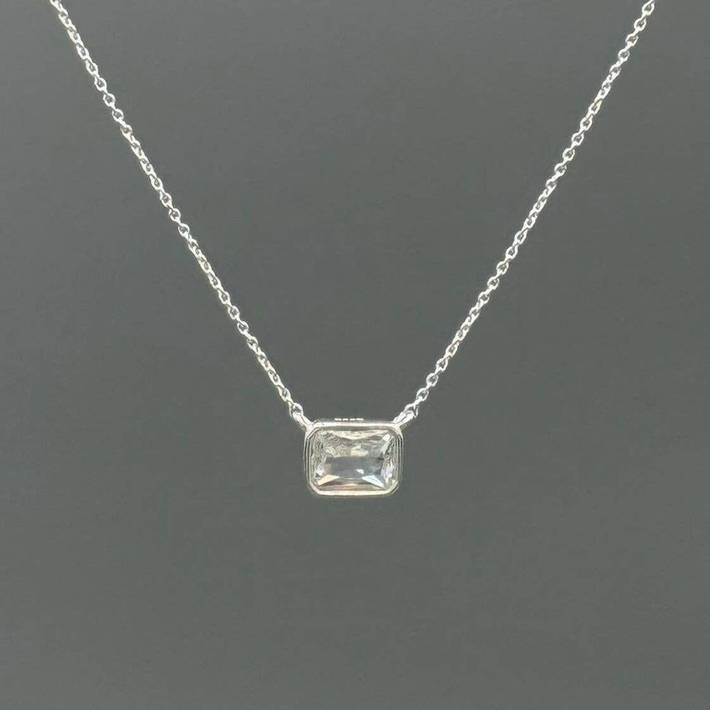 Silver necklace with a rectangular gemstone on a dark gray background