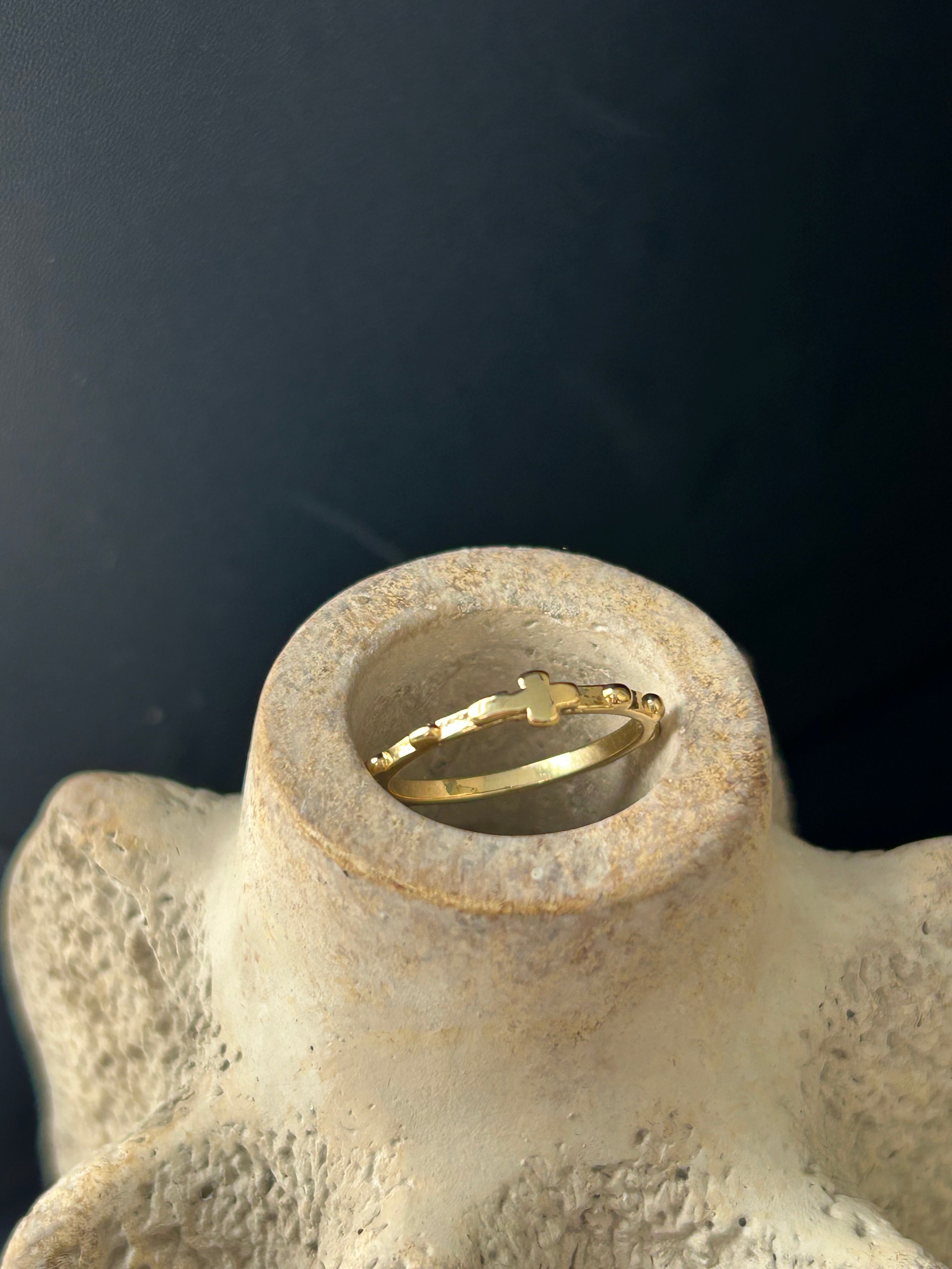 Gold hoop earring on a textured beige surface with a dark background