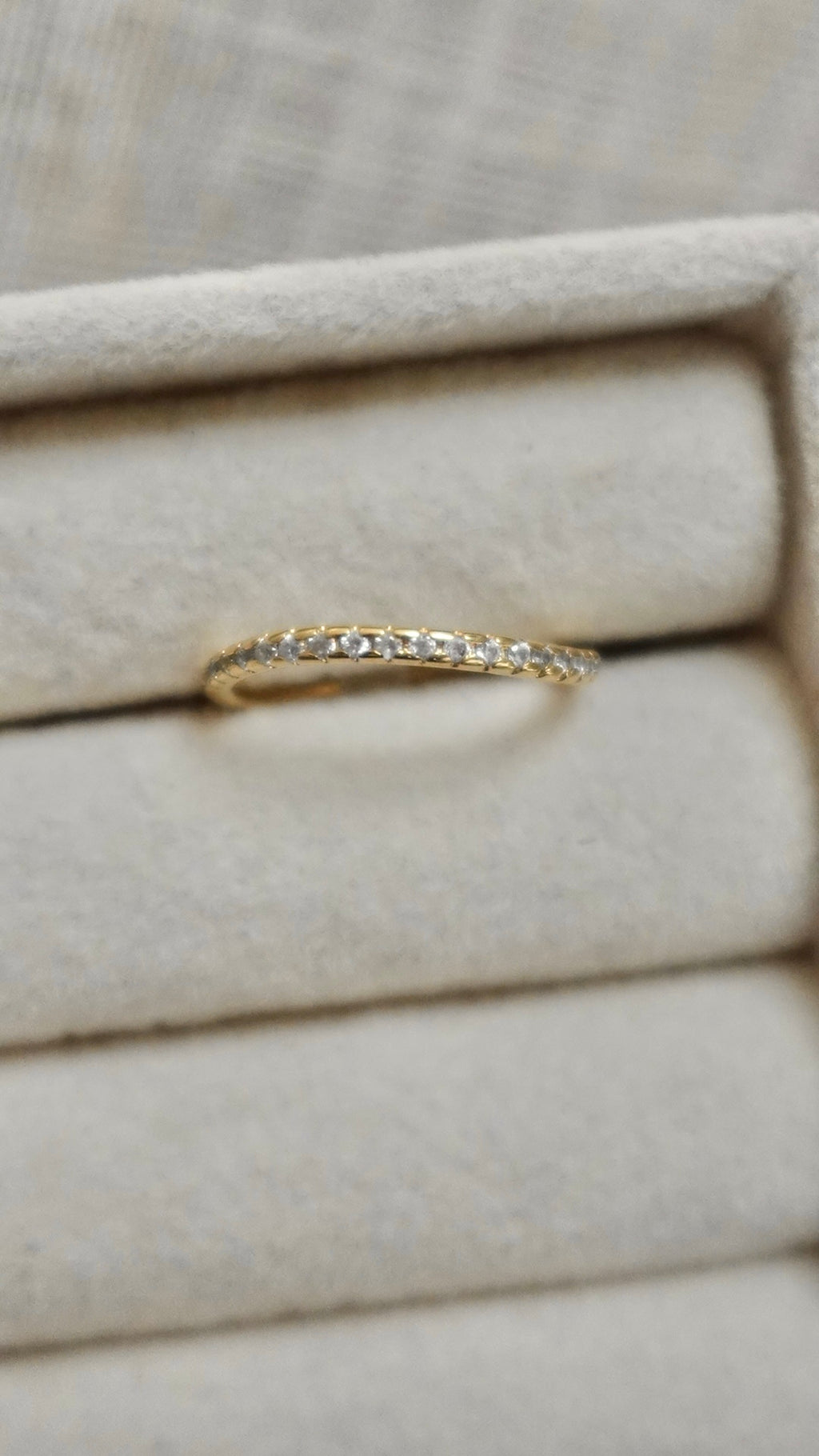 Gold ring with diamonds on a beige fabric background