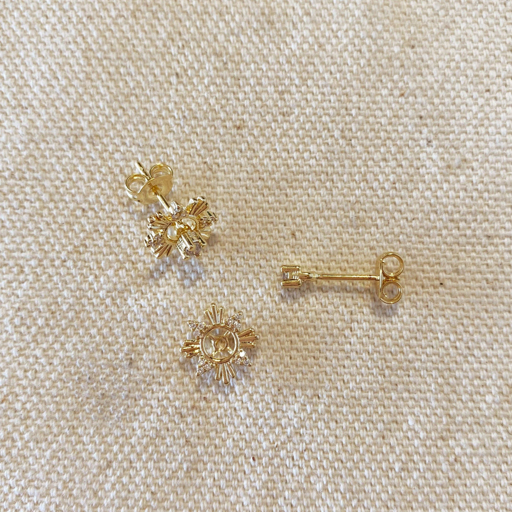 Gold earrings on a beige fabric background