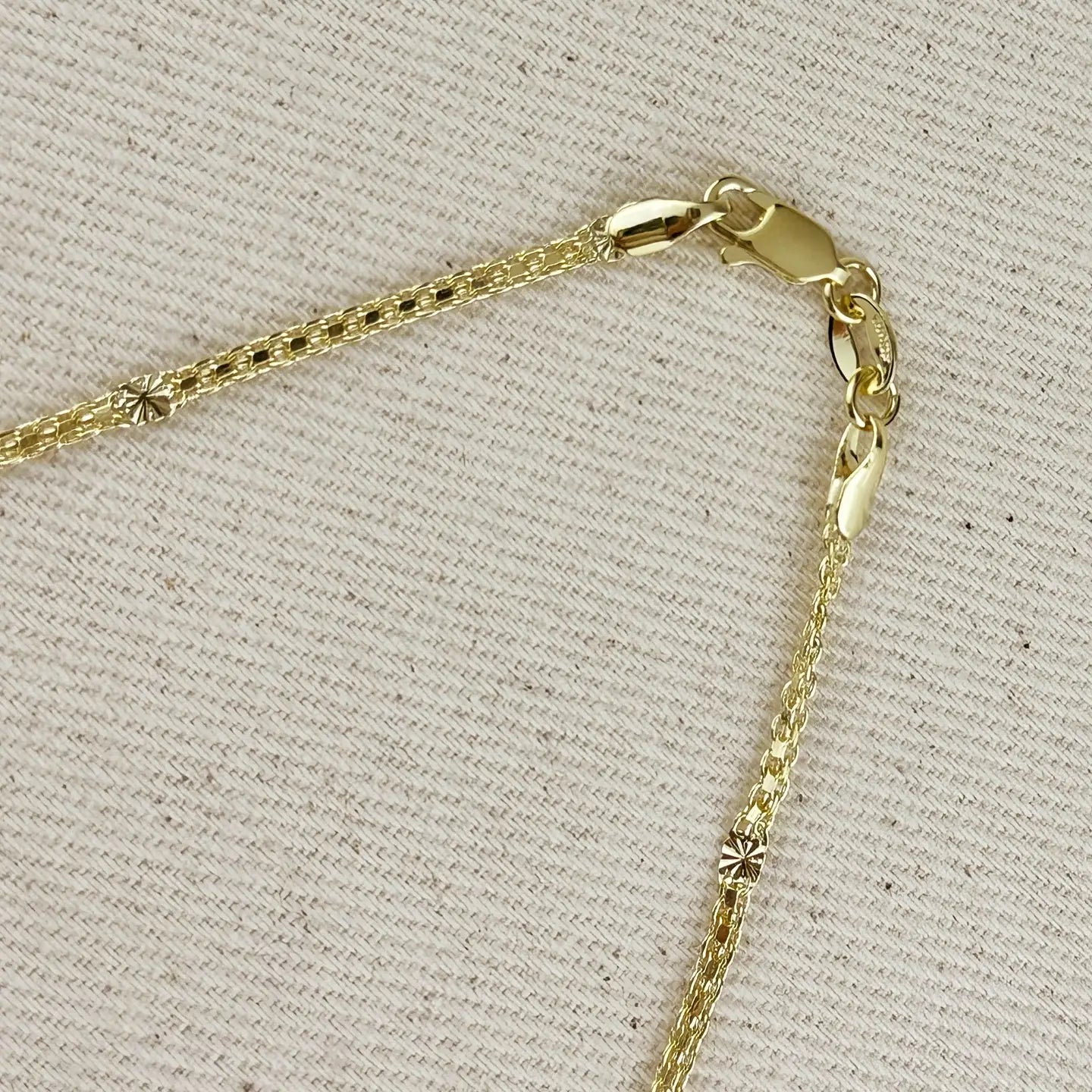Close-up of a gold chain necklace on a textured beige background