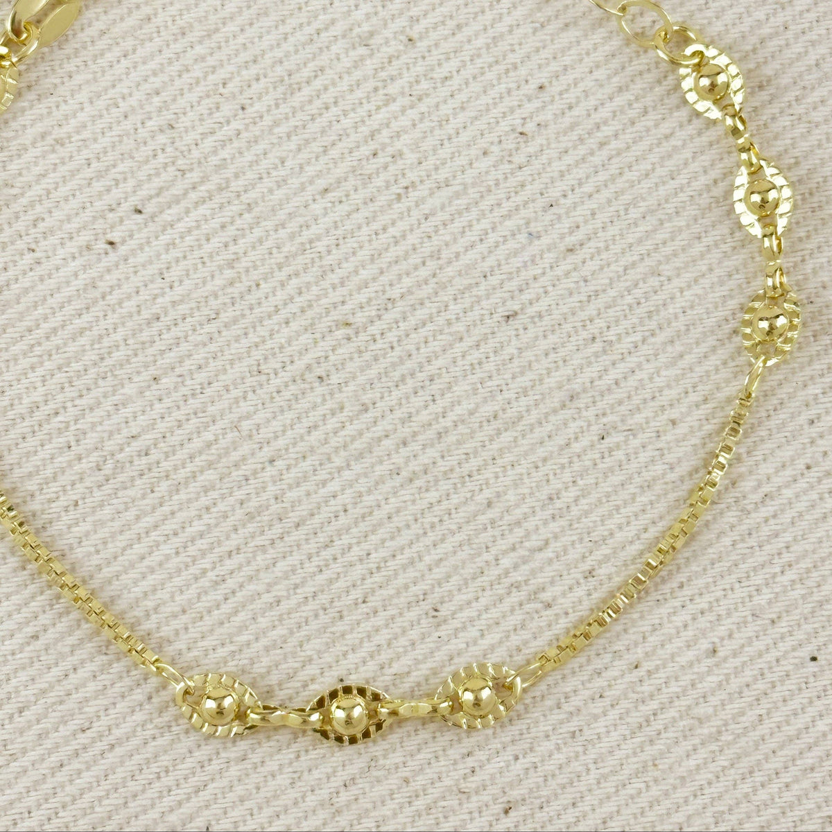 Gold bracelet on a light gray fabric background