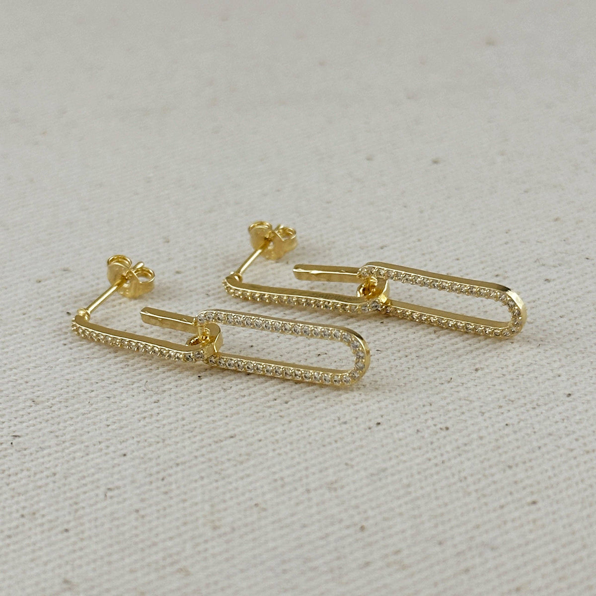Gold safety pin earrings on a light gray background