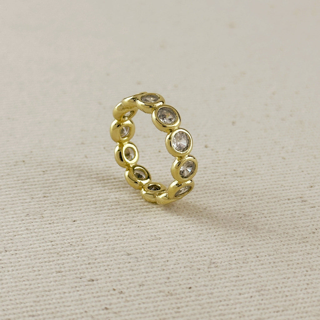 Gold ring with embedded stones on a beige fabric background