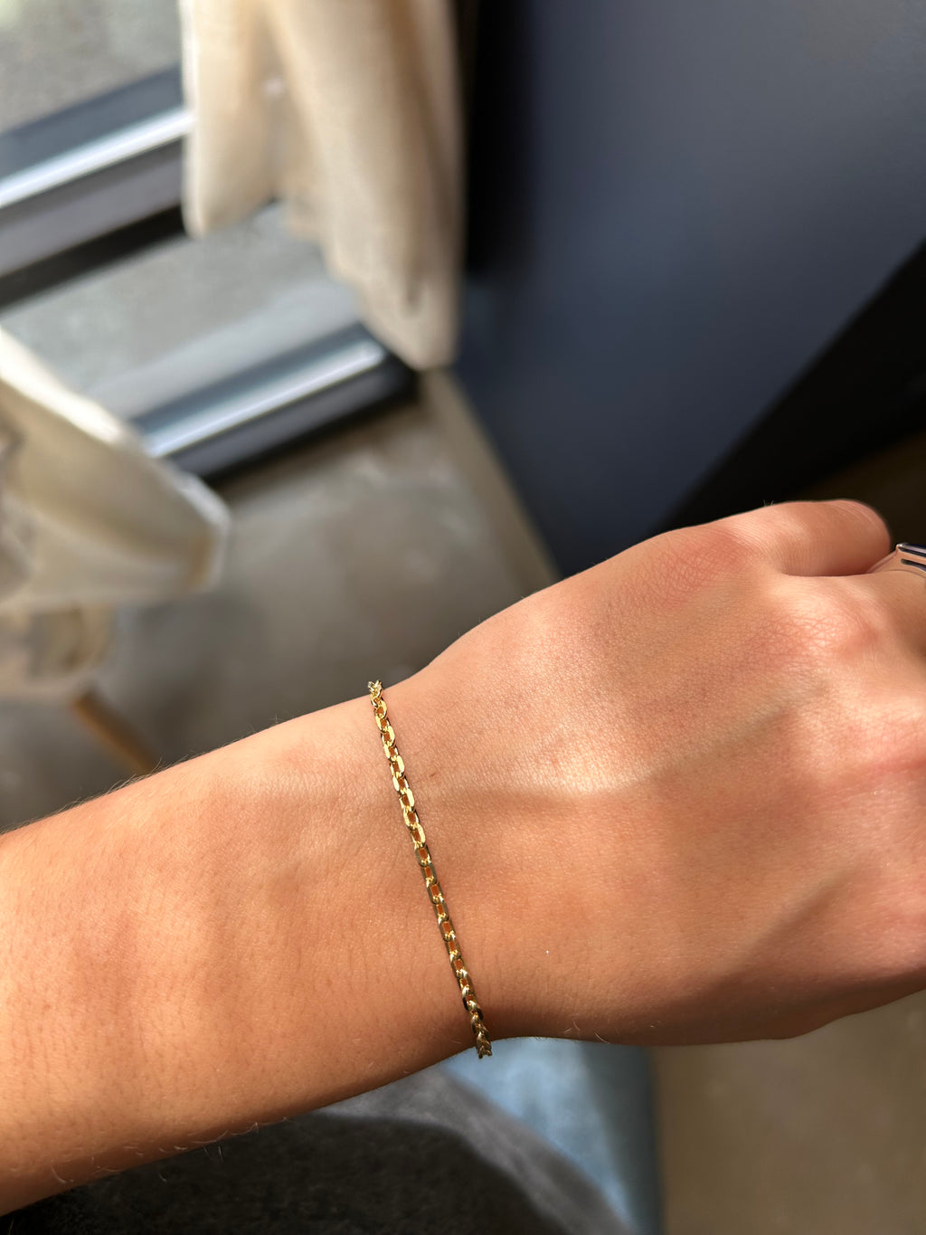 Gold bracelet on a wrist with a blurred background
