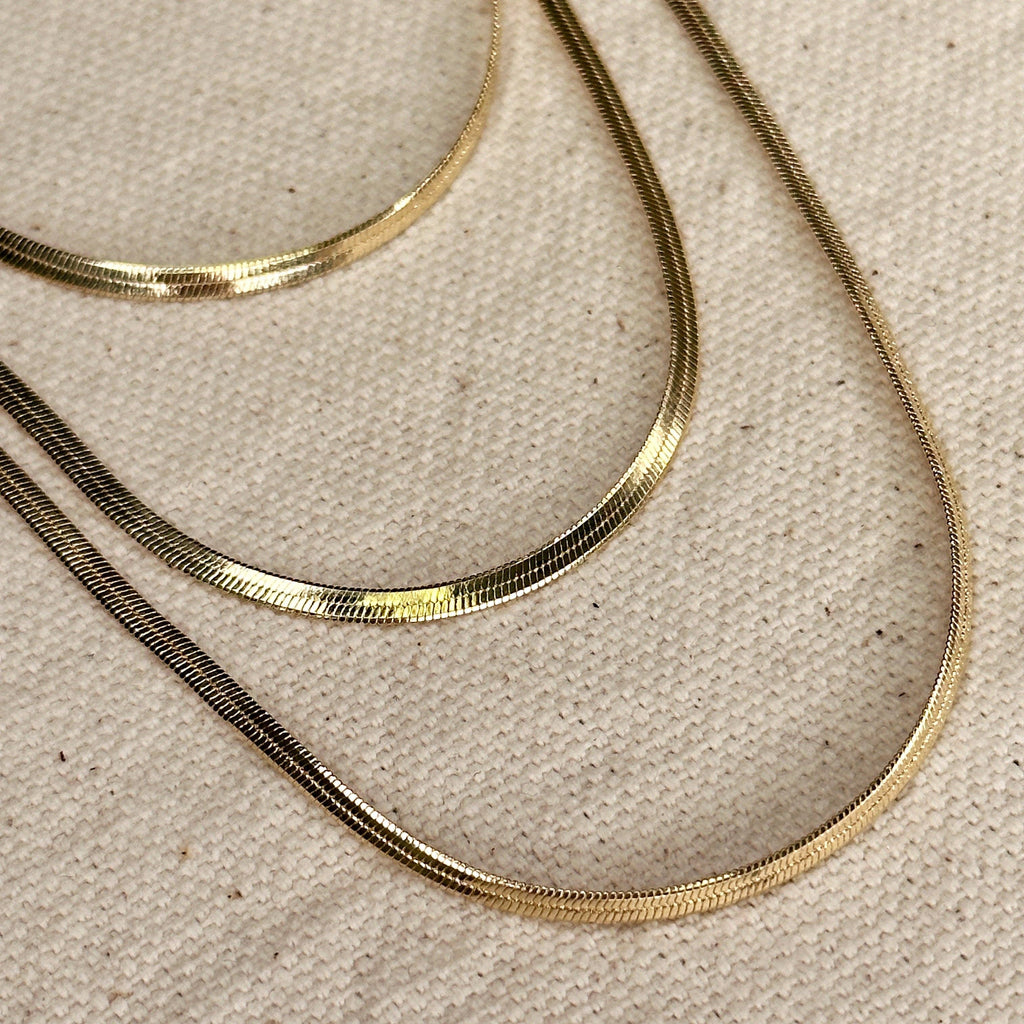 Two gold necklaces on a beige fabric background