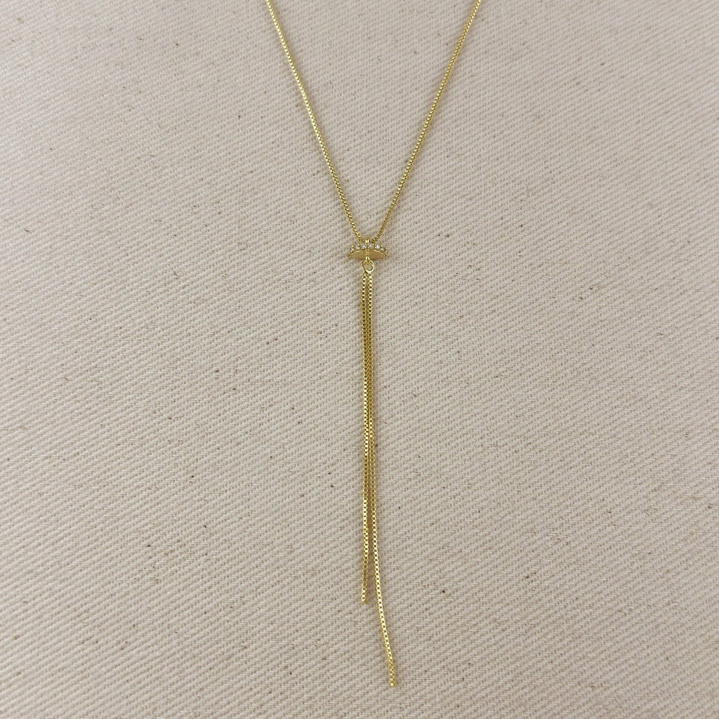 Gold necklace with a tassel on a beige fabric background