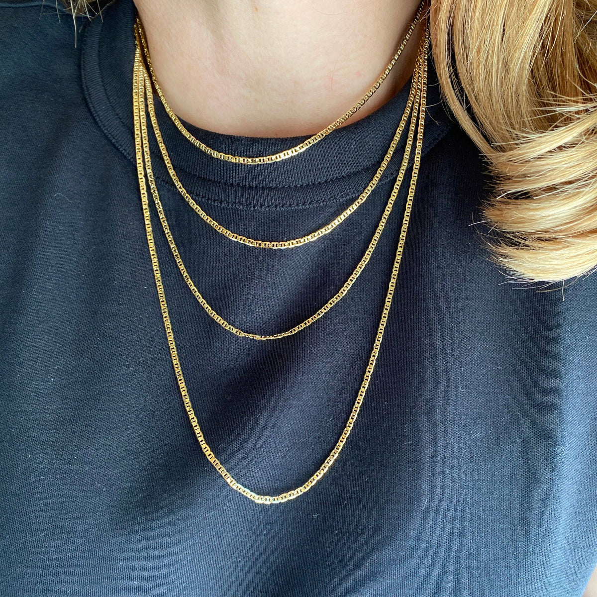 Gold chain necklace on a person wearing a navy blue shirt