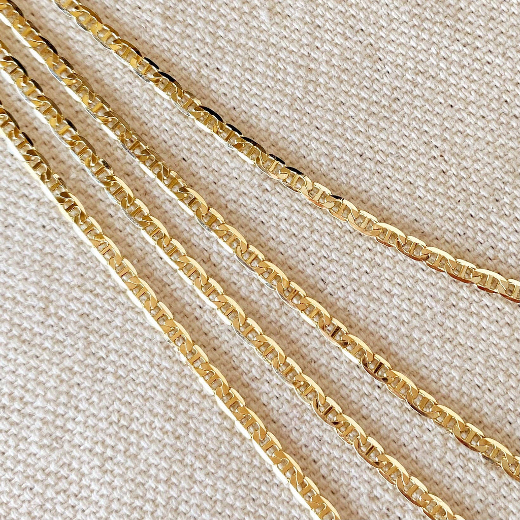Gold chains of different thicknesses on a beige fabric background