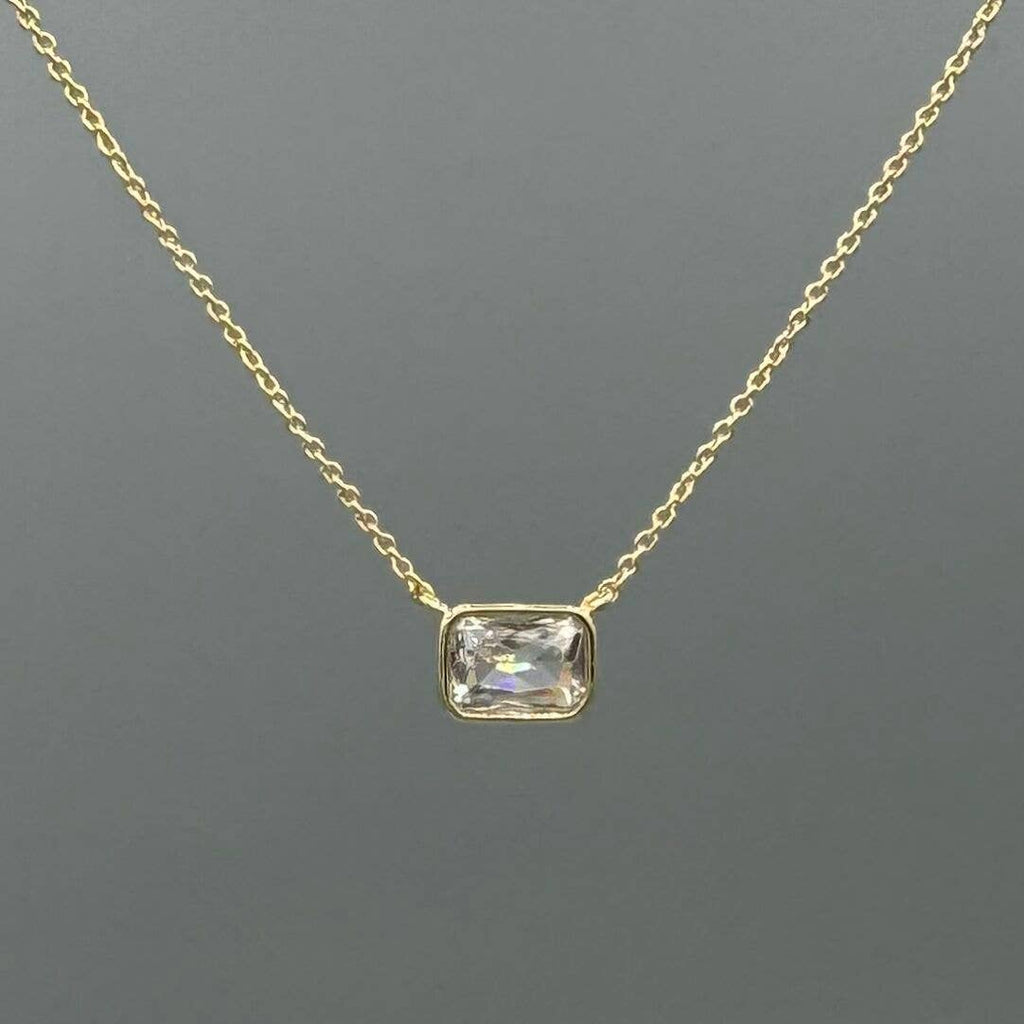 Gold necklace with a rectangular gemstone pendant on a gray background