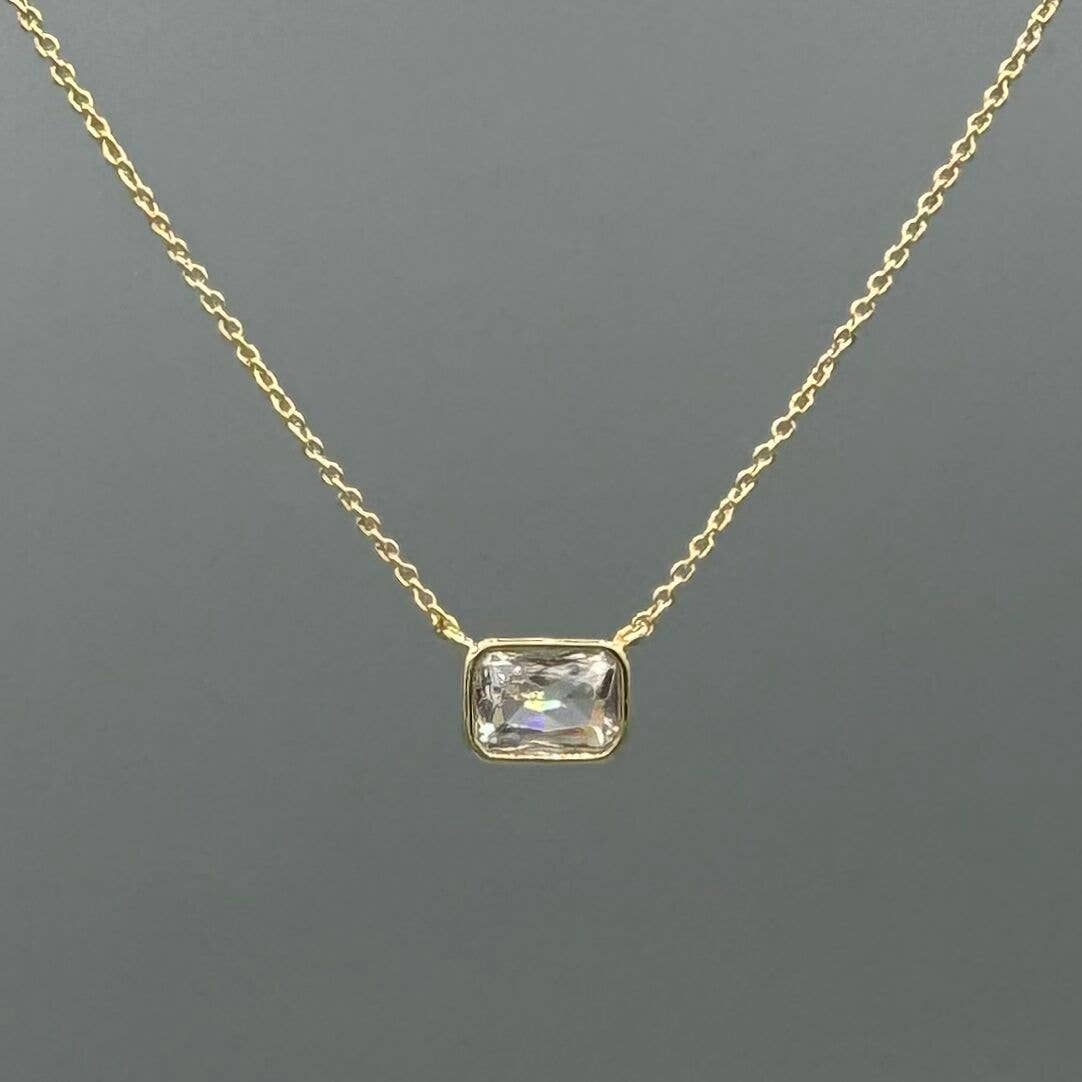Gold necklace with a rectangular gemstone pendant on a gray background