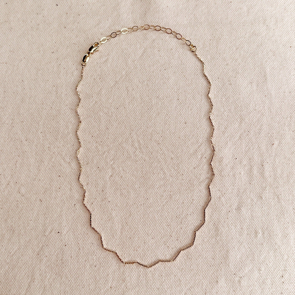 Gold necklace on a beige fabric background