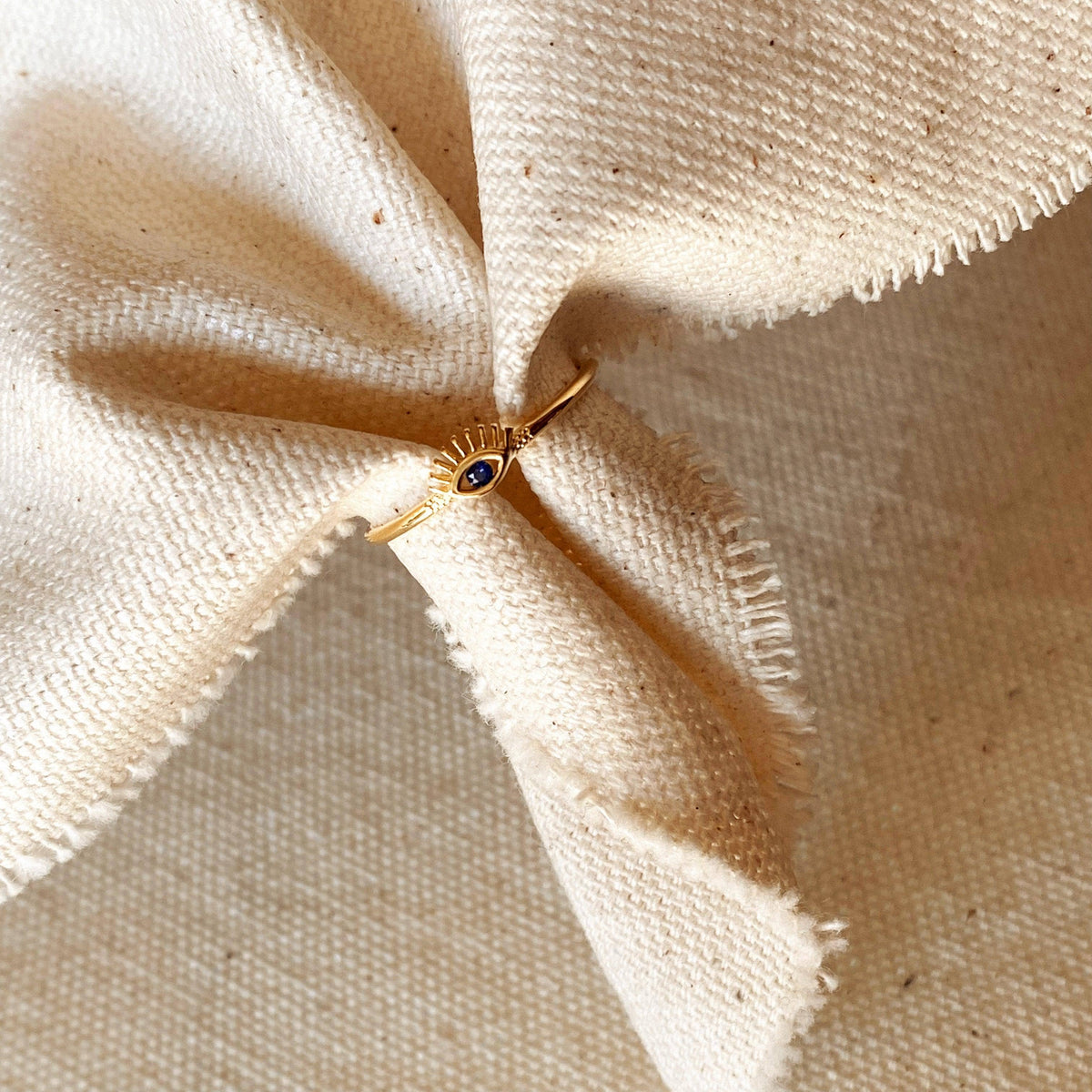 Gold ring with a blue gemstone on beige fabric