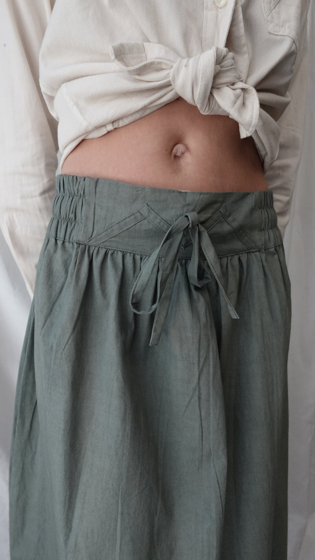 Partial view of a person wearing a green dress with a white shirt underneath.