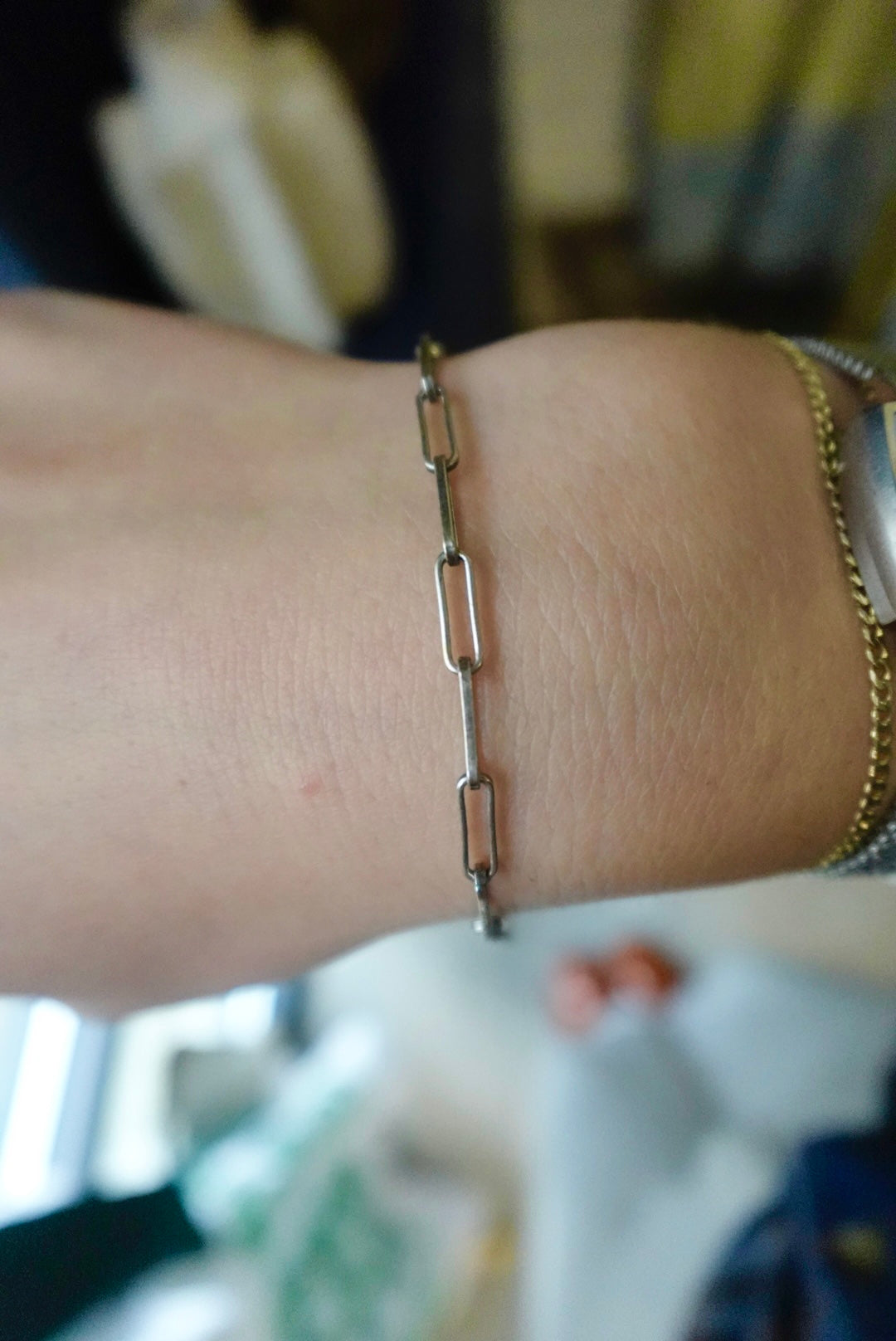 Gold chain bracelet on a wrist with a blurred background