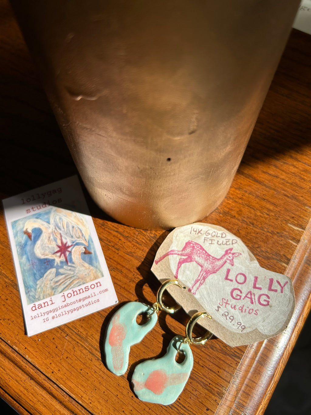 Pair of earrings with a 'Lolly Gag' box on a wooden surface