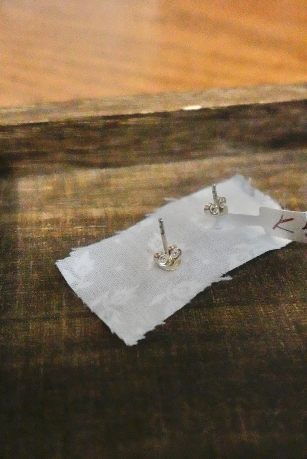 Pair of silver earrings on a white card with a wooden surface background