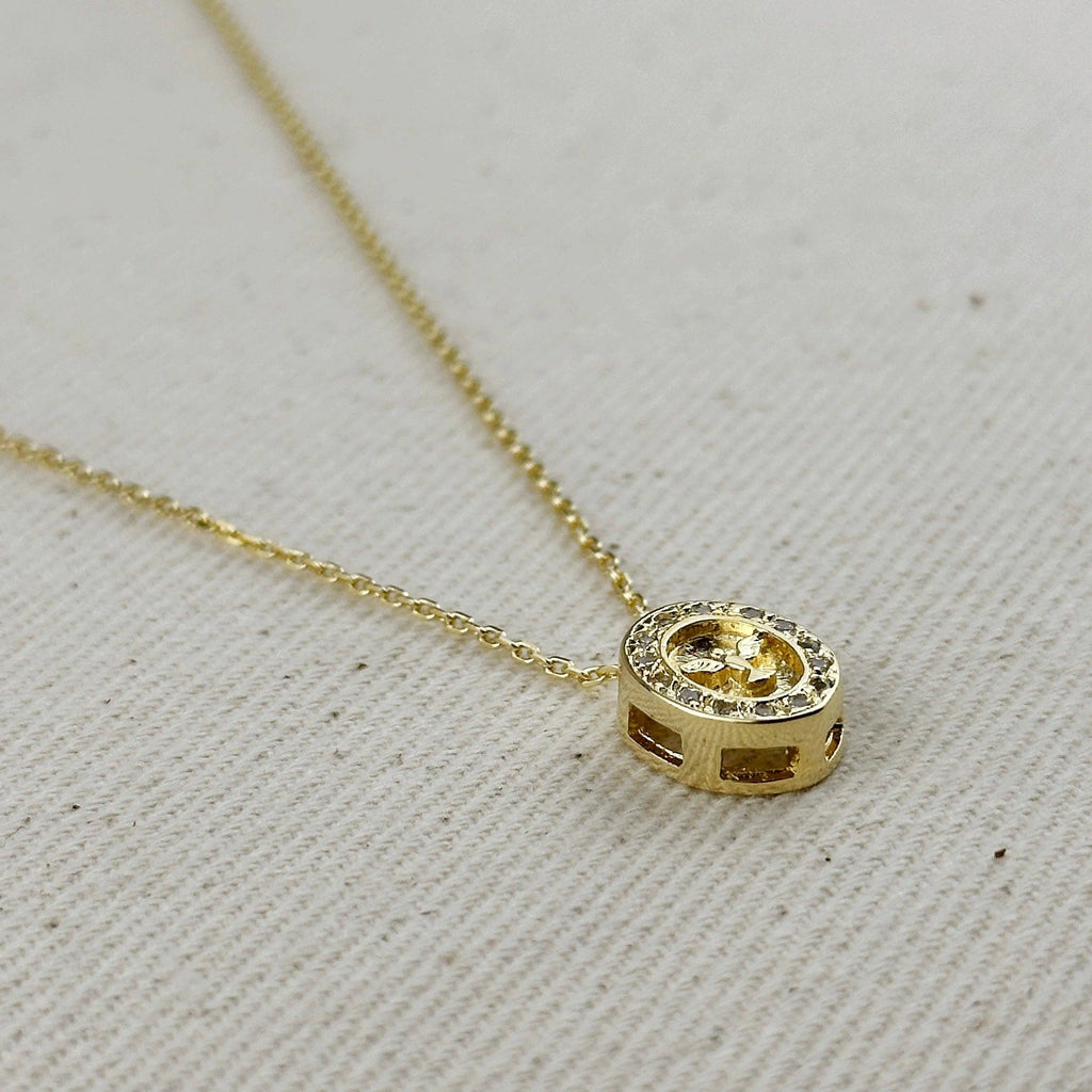 Gold necklace with a round pendant on a light gray background