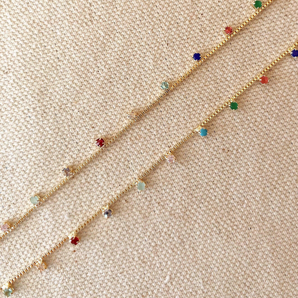 Gold bracelet with colorful beads on a beige fabric background