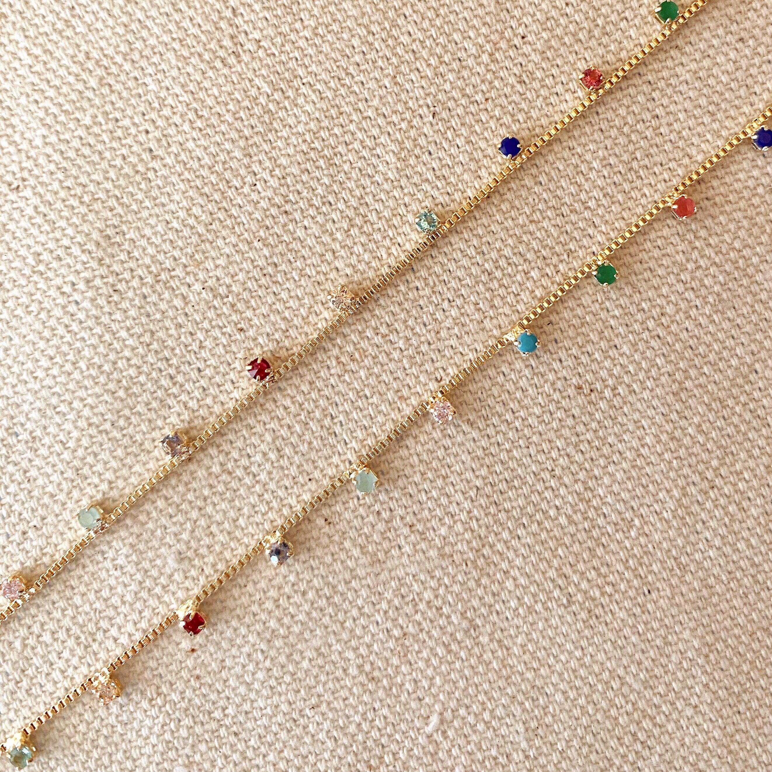 Gold bracelet with colorful beads on a beige fabric background