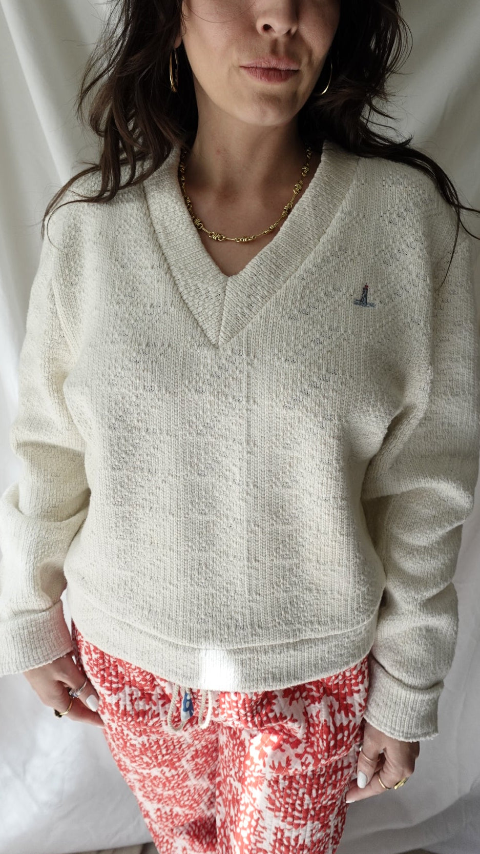 Woman wearing a white sweater and red patterned skirt on a white background