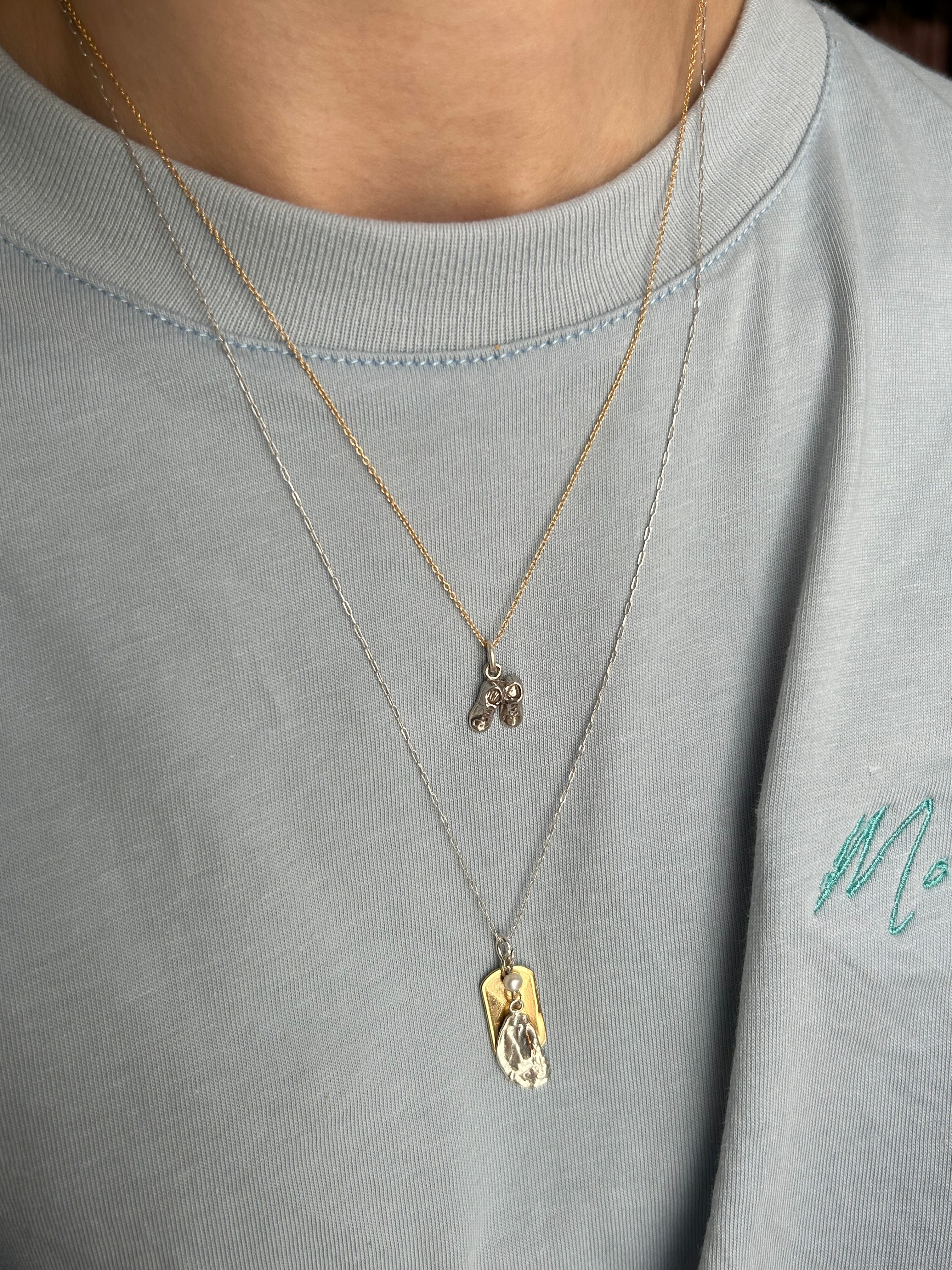 Gold necklace with a pendant on a gray shirt