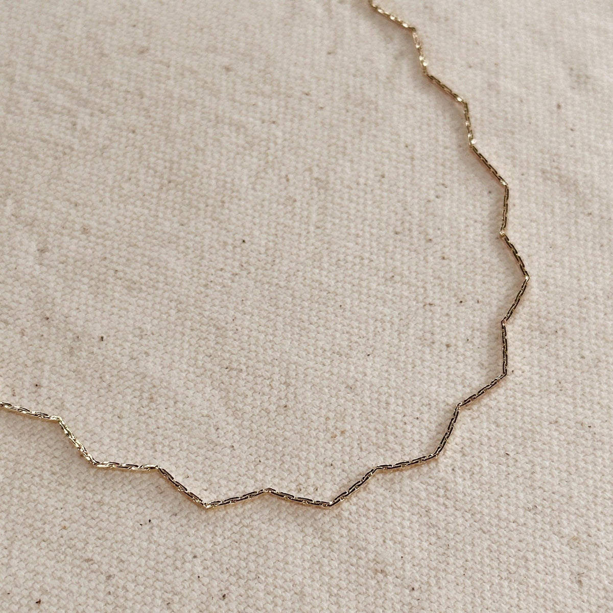 Gold necklace on a beige fabric background