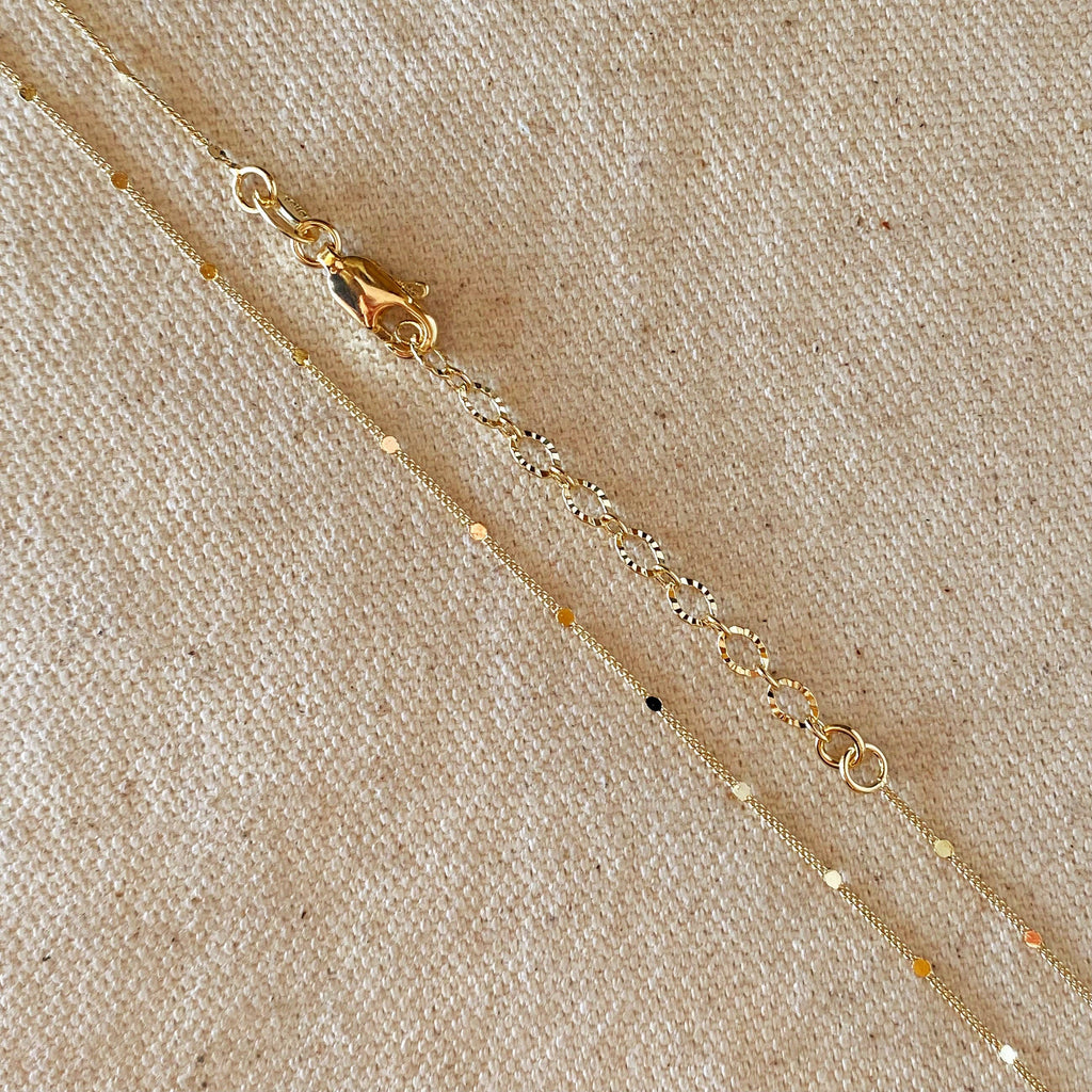 Gold necklace with small beads on a beige fabric background
