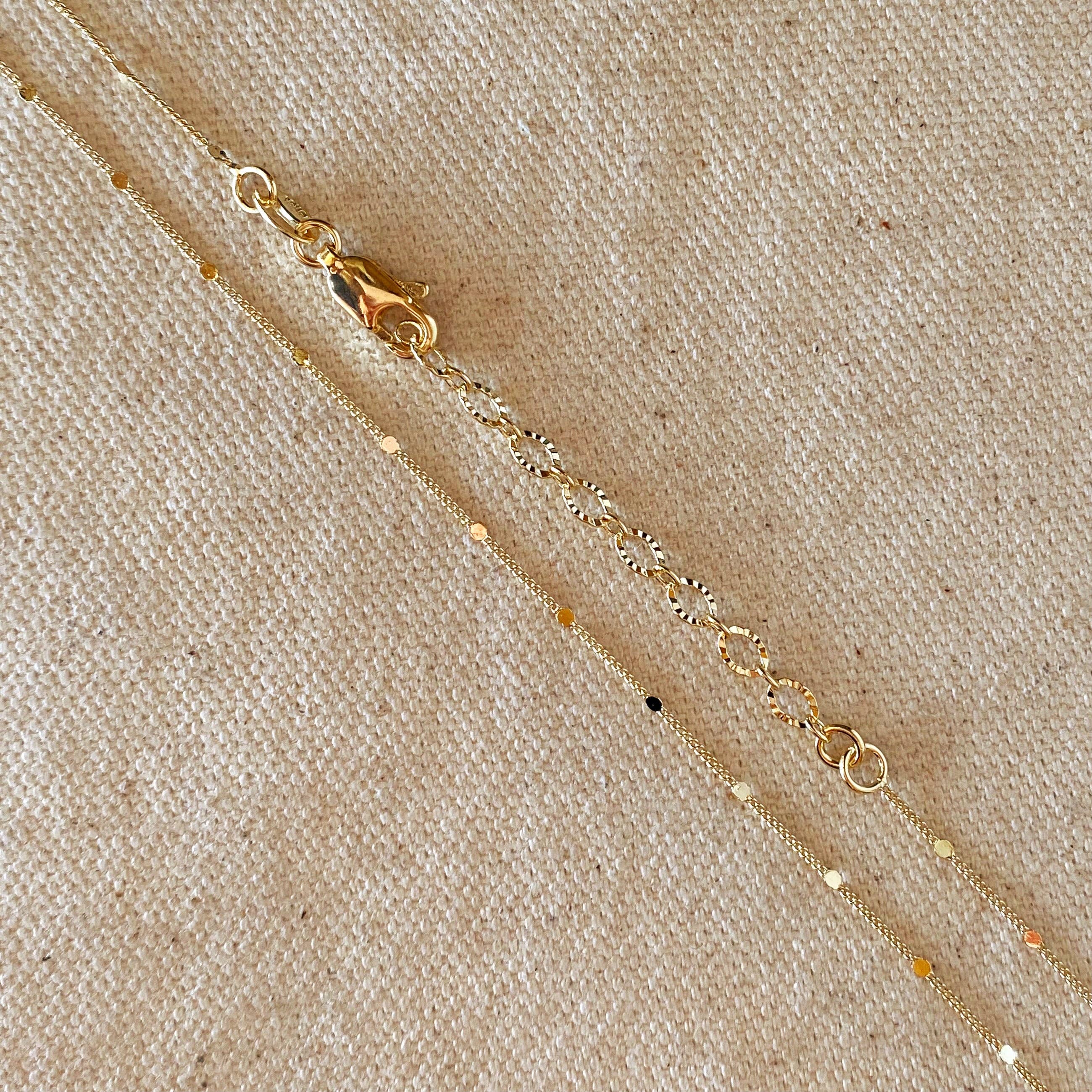 Gold necklace with small beads on a beige fabric background
