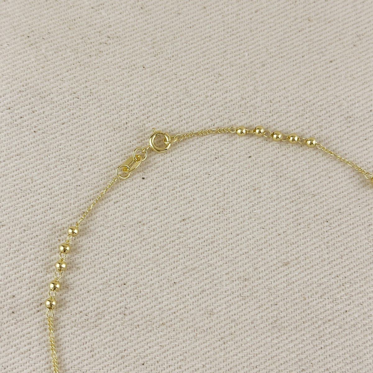 Gold bracelet on a beige fabric background