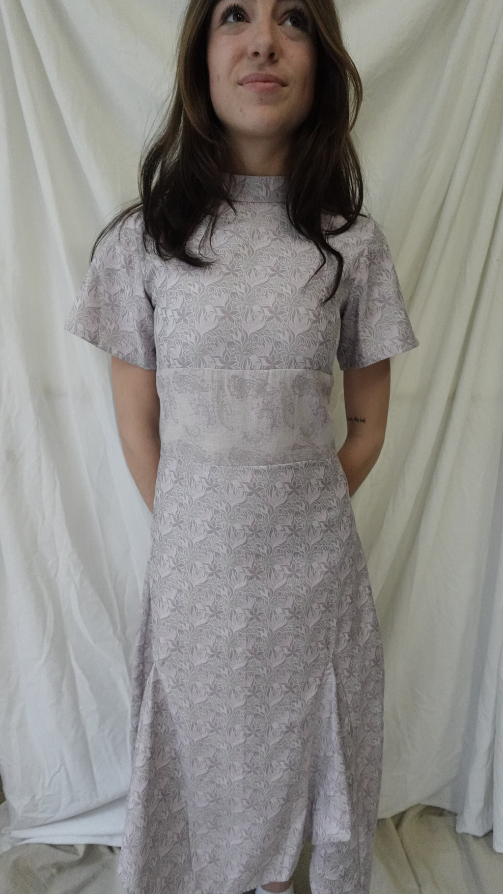 Woman wearing a silver lace dress lying on a white fabric surface