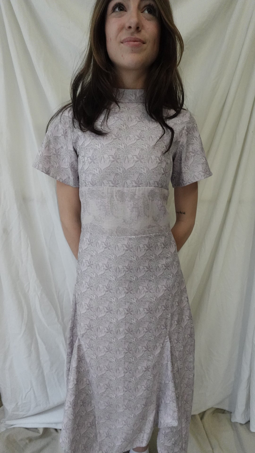 Woman wearing a silver lace dress lying on a white fabric surface