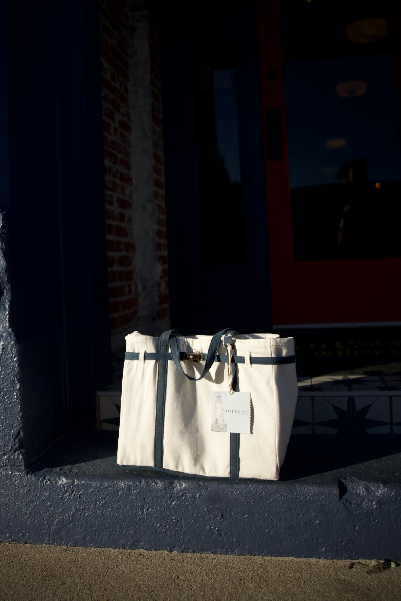 Beige tote bag with black strap on a dark surface