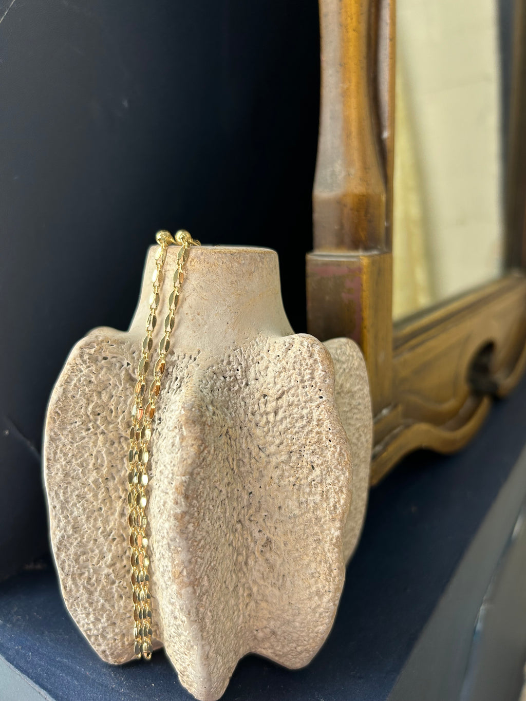 Close-up of a decorative metal object with a gold chain on a dark background