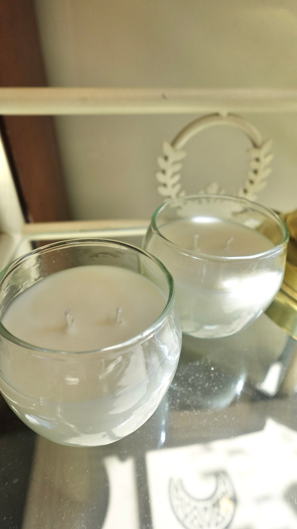 Two glass containers with white candle wax on a reflective surface.