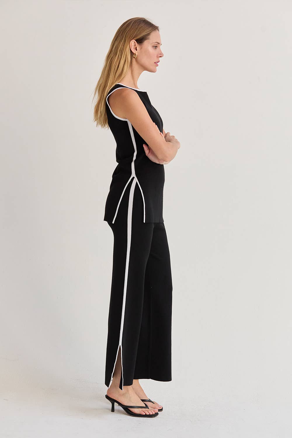 Woman wearing a black outfit with white stripes on a plain background
