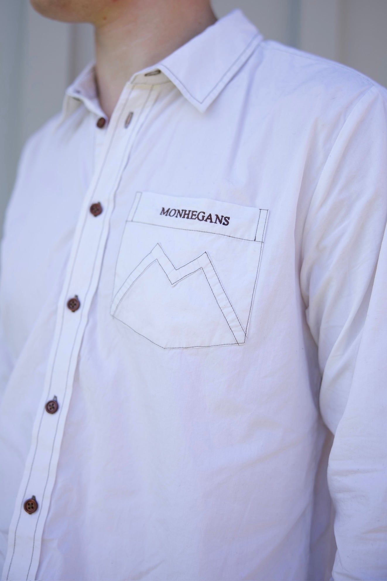 White shirt with a visible brand logo on a neutral background