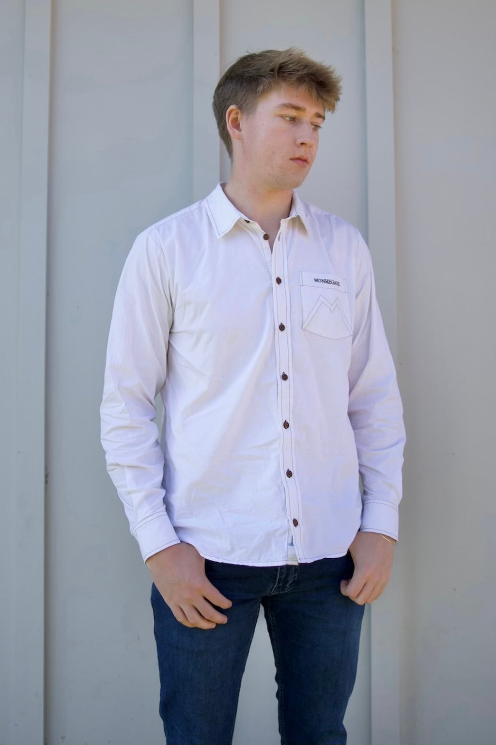 Person wearing a light purple button-up shirt and dark jeans against a plain background