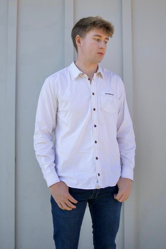 Person wearing a light purple button-up shirt and dark jeans against a plain background