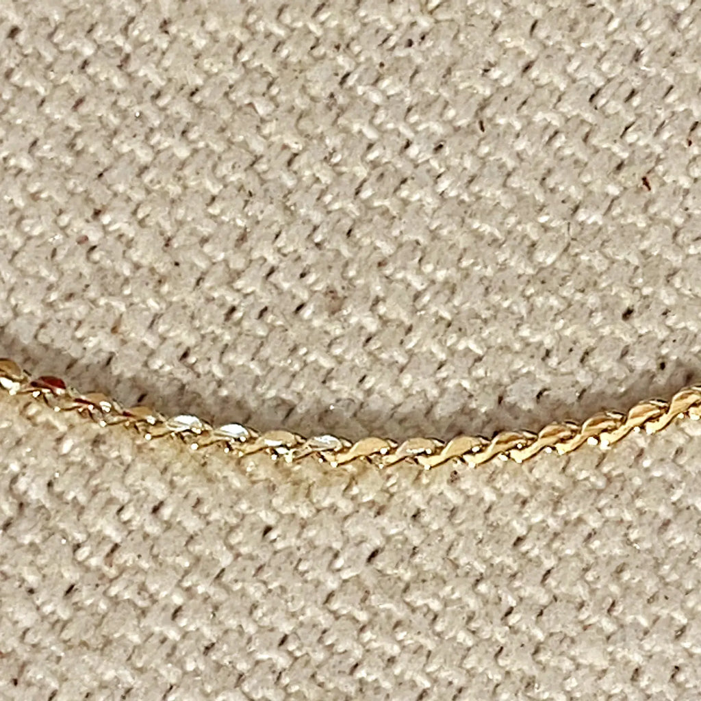 Close-up of a gold chain on a beige textured background