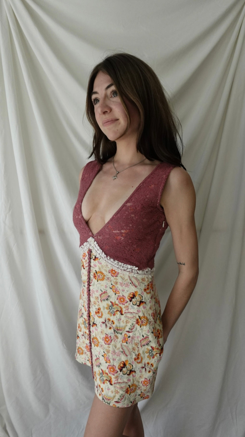Woman wearing a burgundy top and floral skirt against a plain background