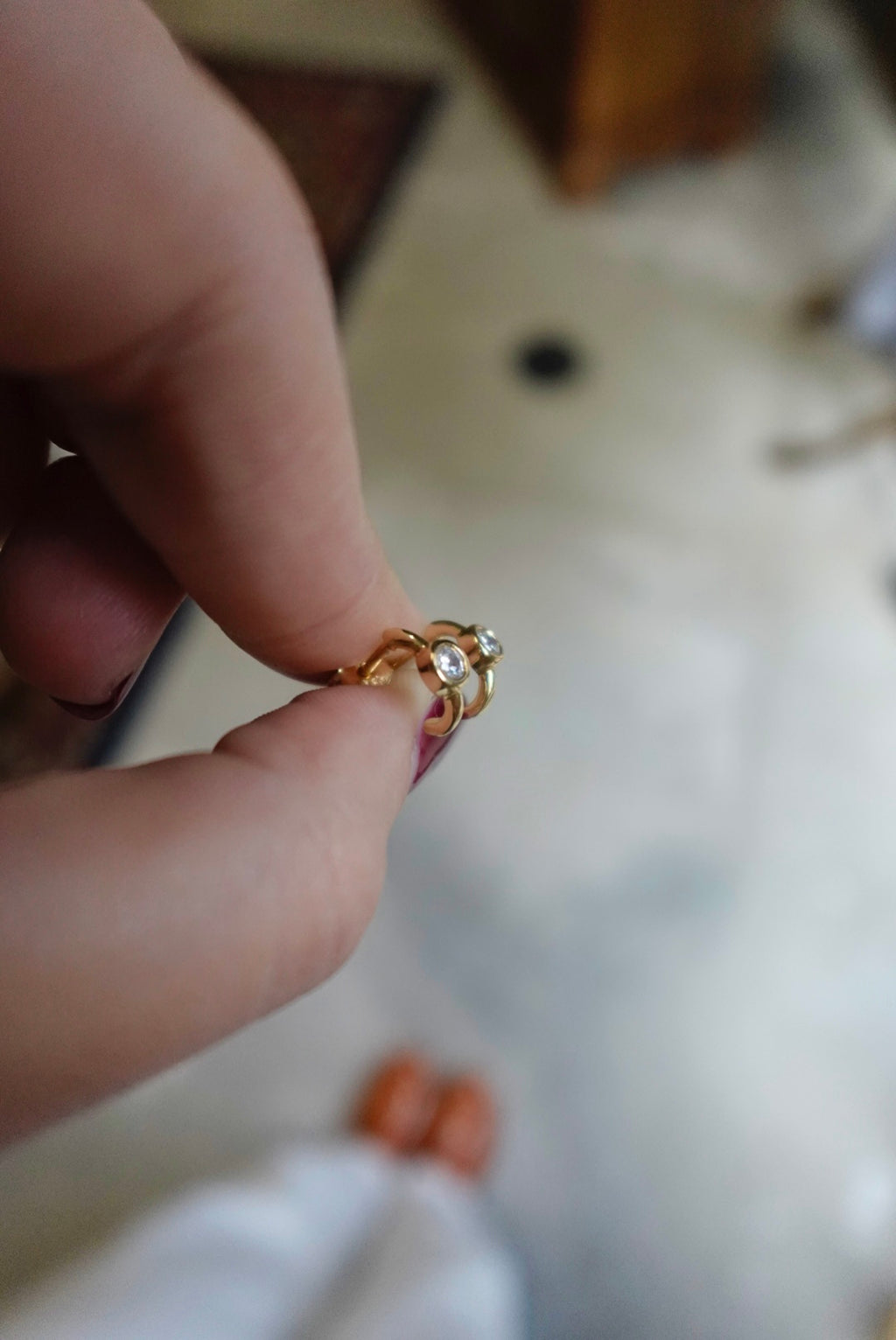 Gold ring with a diamond held between fingers against a blurred background