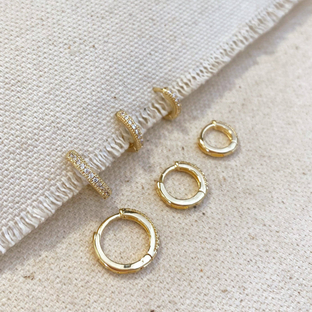 Set of gold hoop earrings on a textured beige surface