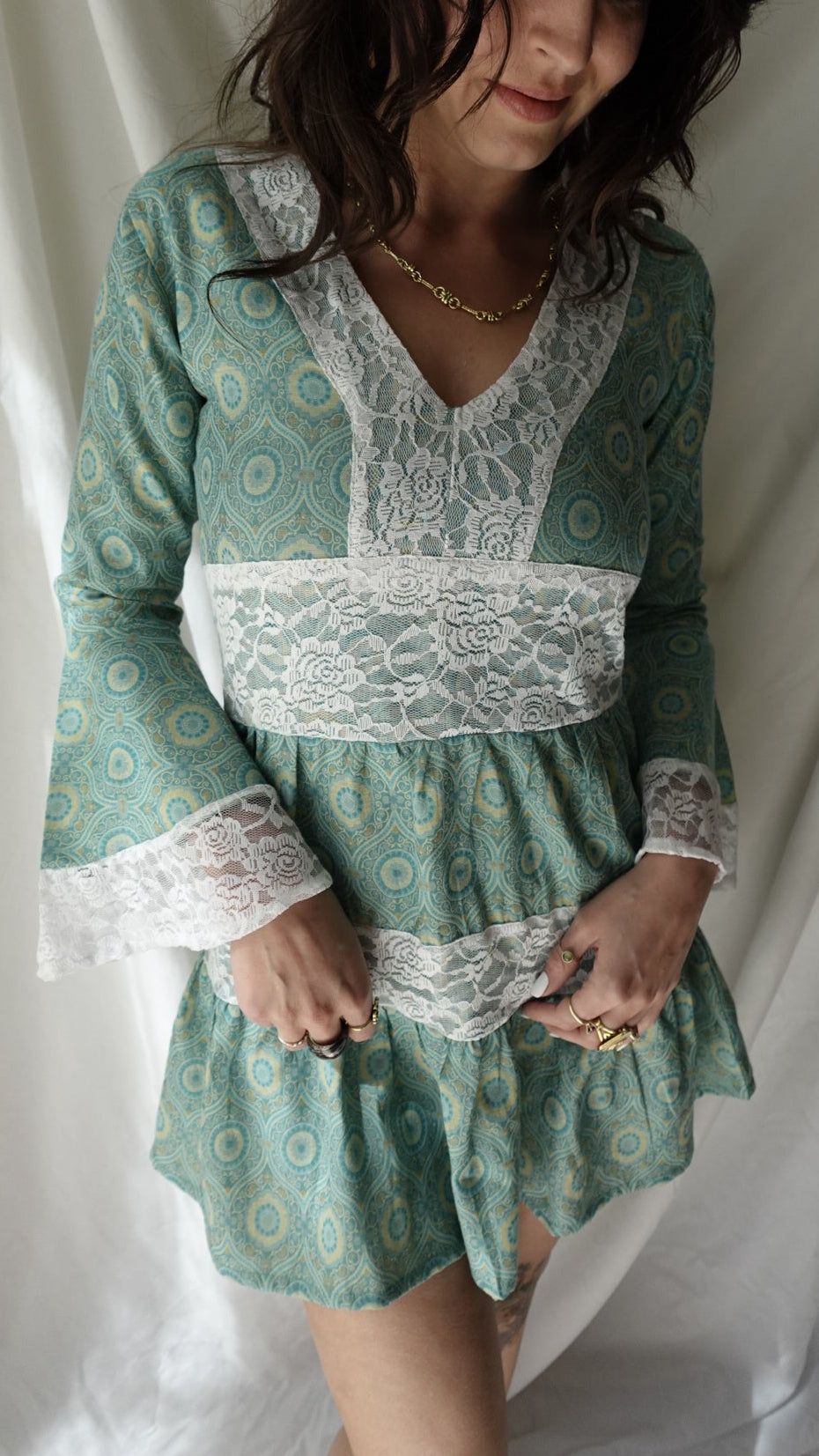 Woman wearing a green patterned dress with lace details on a white background
