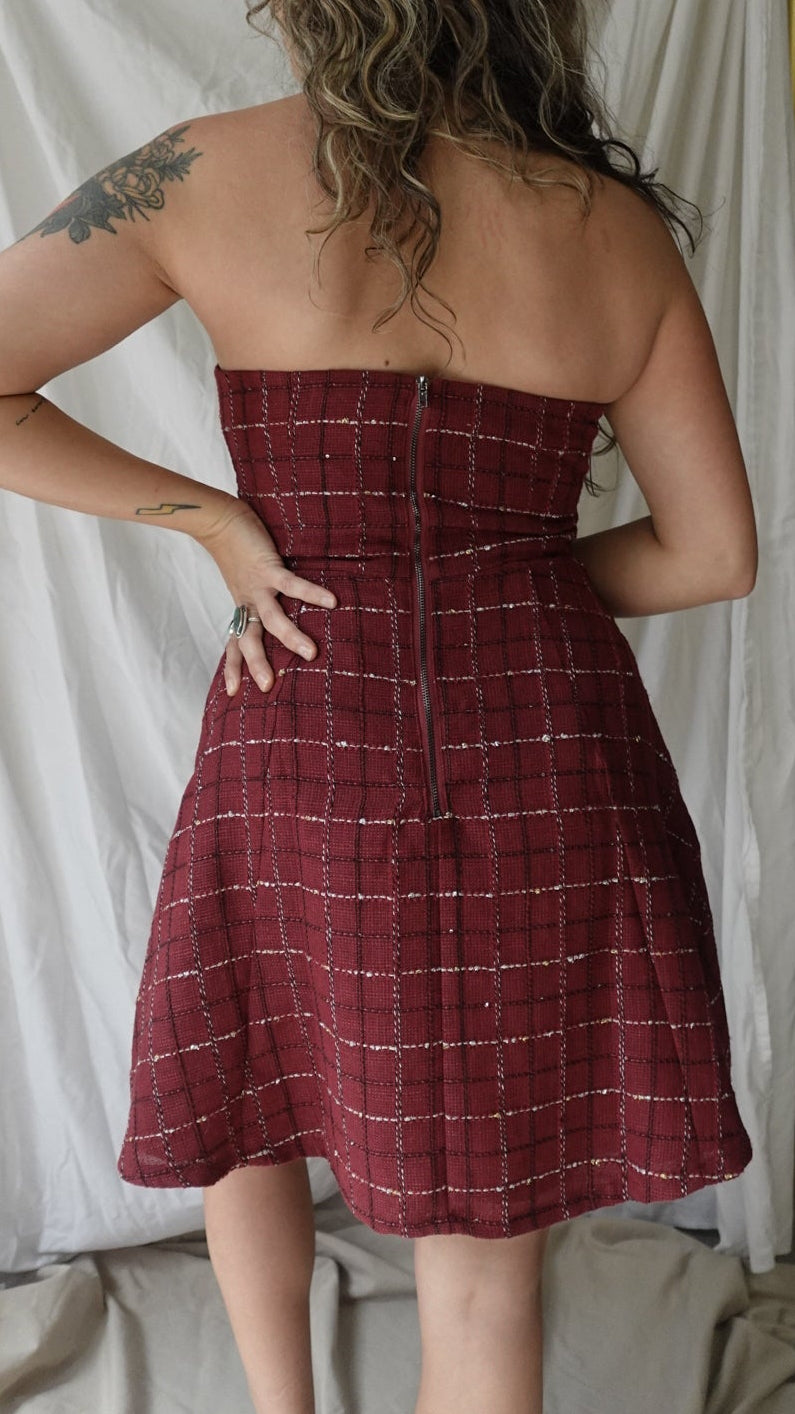 Woman in a red checkered dress lying on a bed