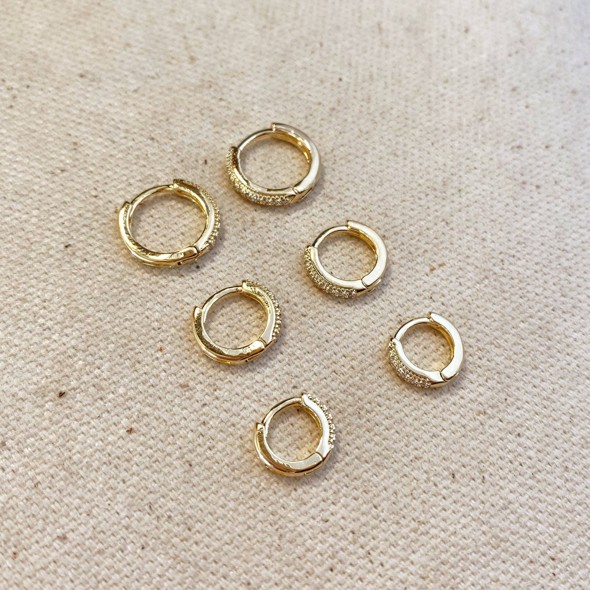 Gold hoop earrings on a textured beige surface