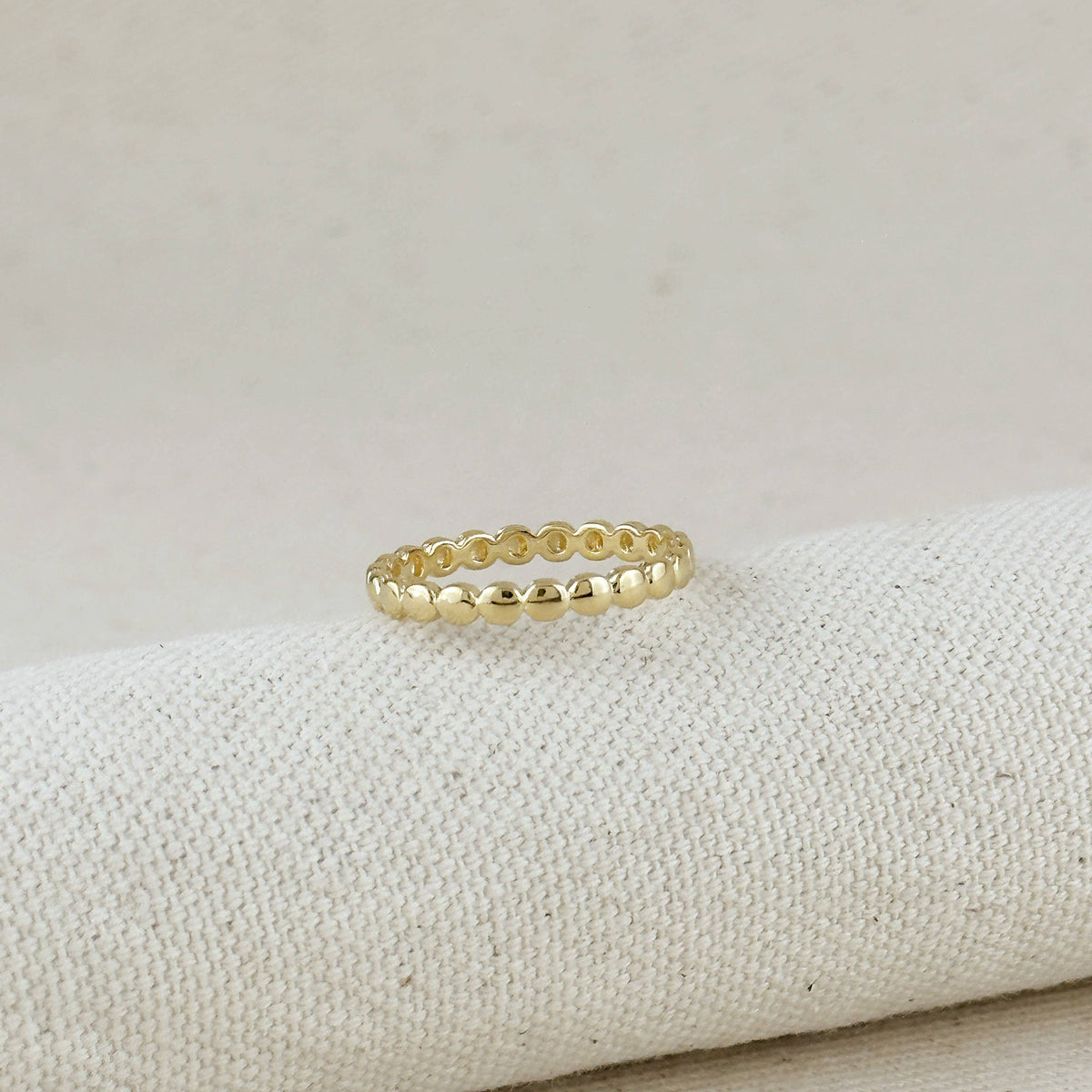 Gold ring on a textured beige surface