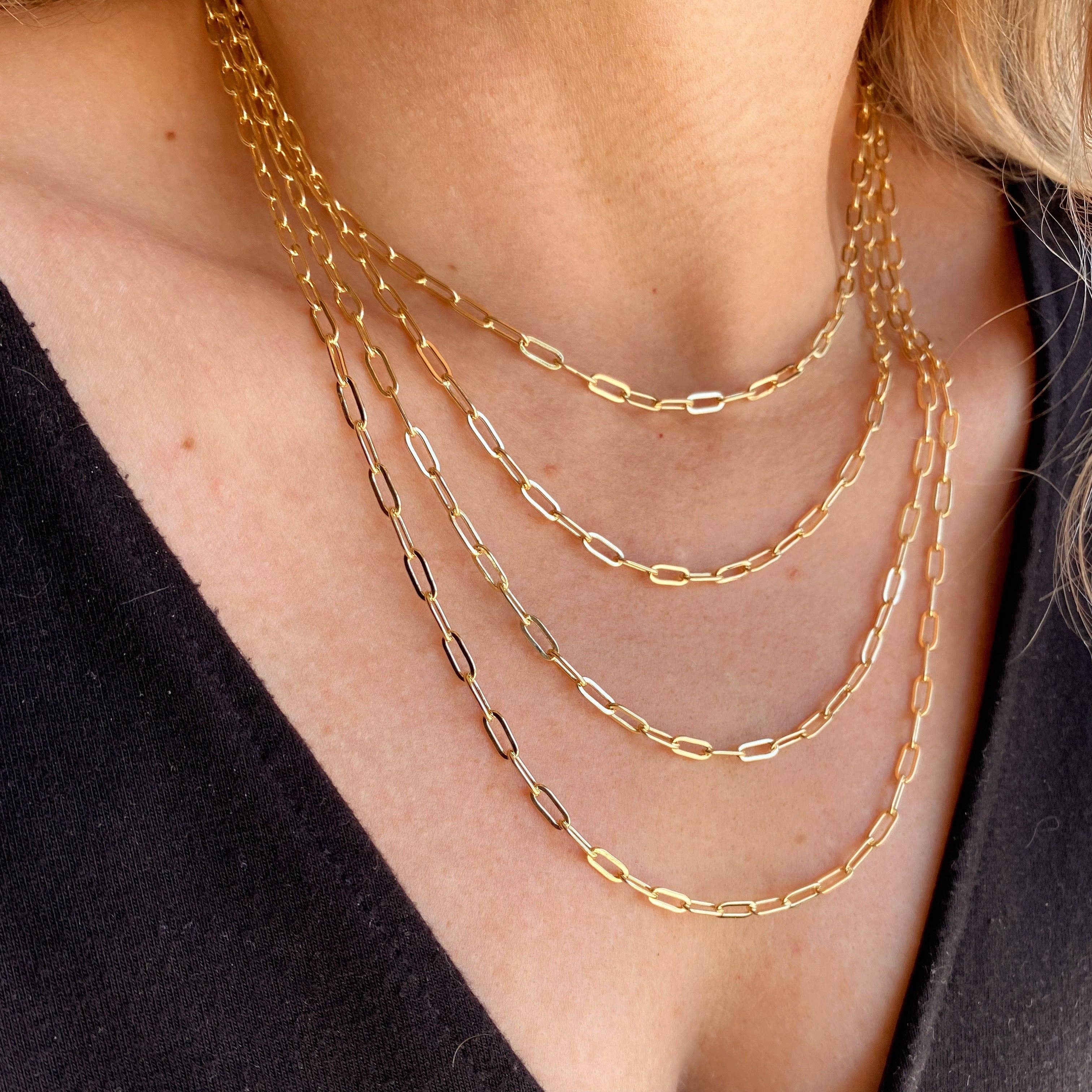 Gold chain necklaces on a person wearing a black top