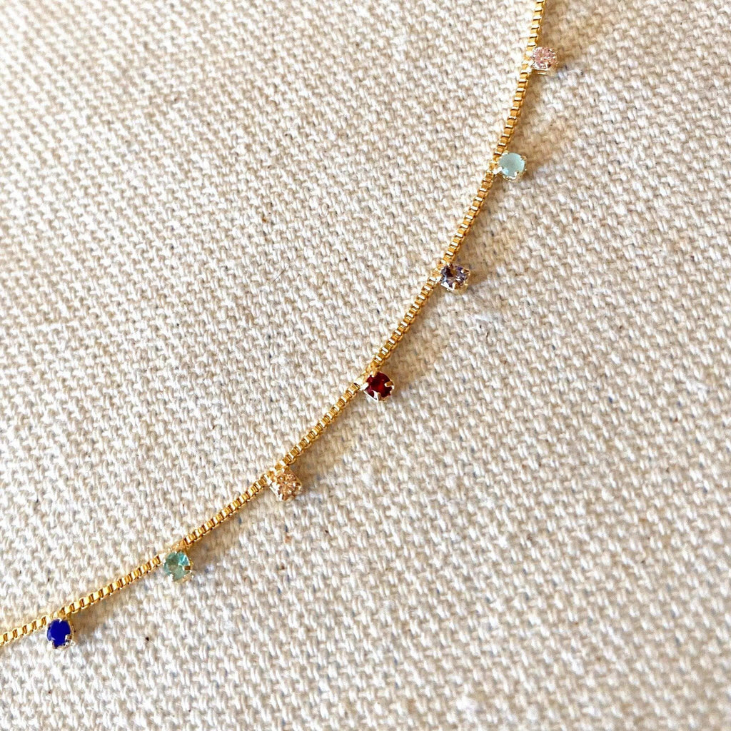 Gold necklace with colorful beads on a beige fabric background